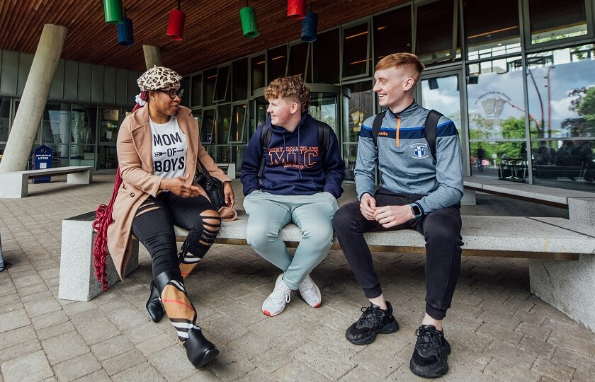 Three students sitting outside Tara building in MIC Limerick campus.