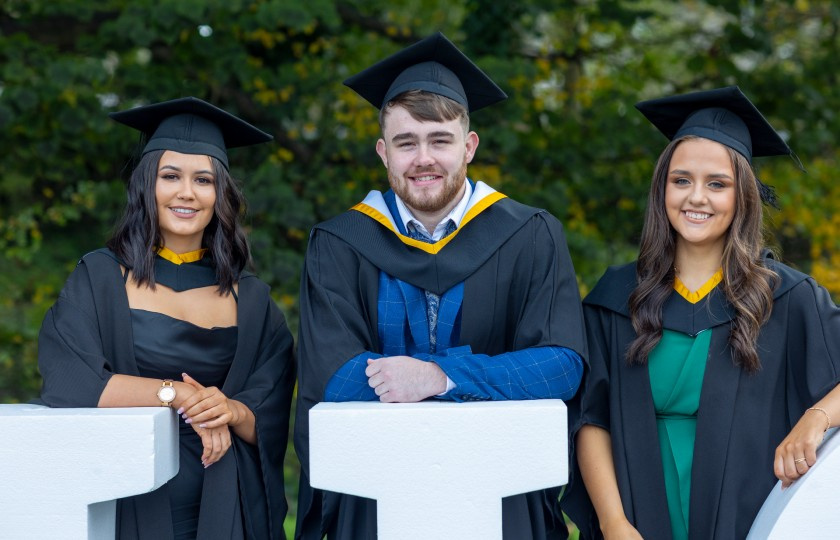 Three graduates on their graduation day.