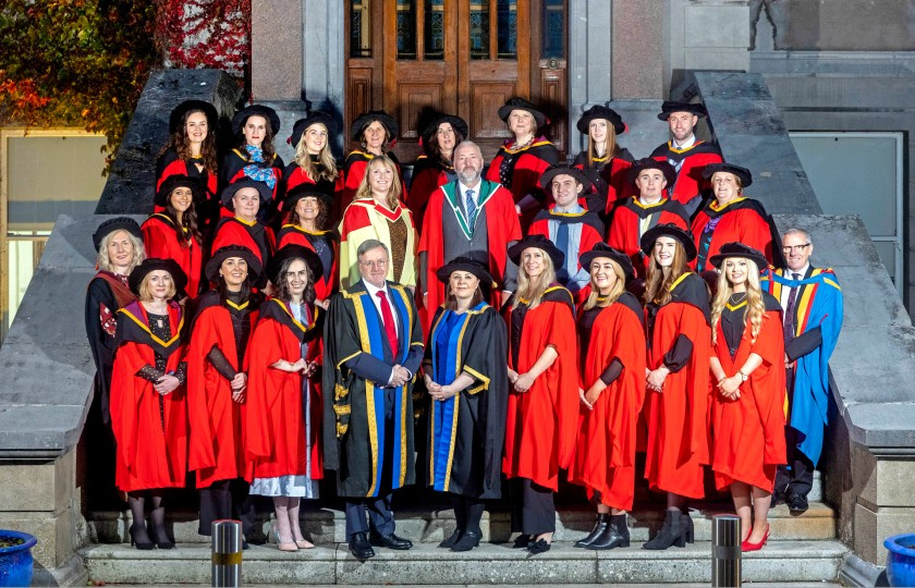 MIC PhD graduates standing on college steps