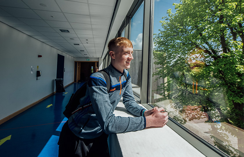 Male student standing at the window looking out on MIC Limerick campus.