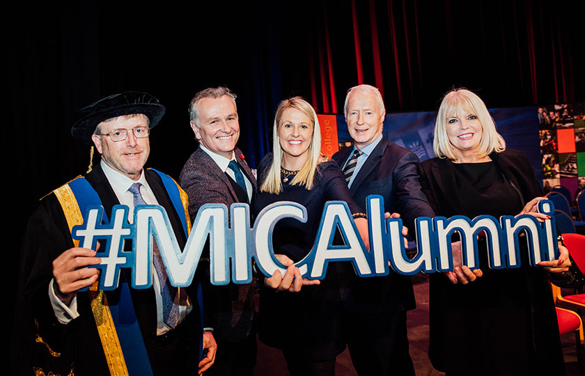 Prof Eugene Wall, Dáithí Ó Sé, Jacqui Hurley, Éamonn Meehan, and Mary Mitchell O’Connor holding an #MICAlumni sign.