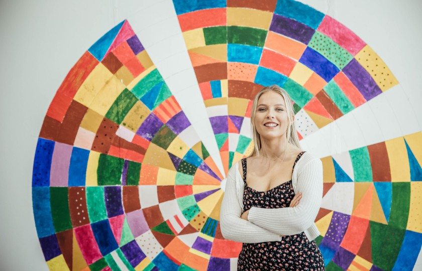 MIC student standing in front of her work at the end of year art exhibition.