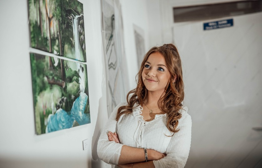 MIC student standing in front of her work at the end of year art exhibition.