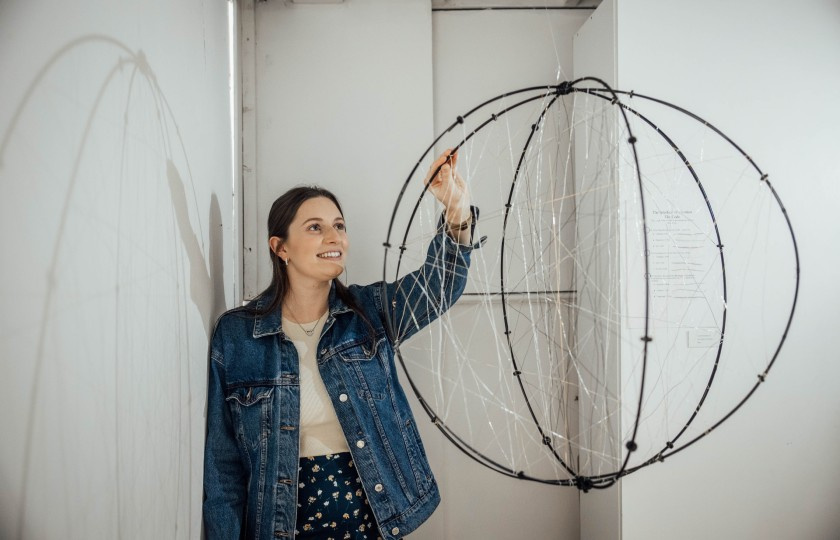 MIC student standing in front of her work at the end of year art exhibition.