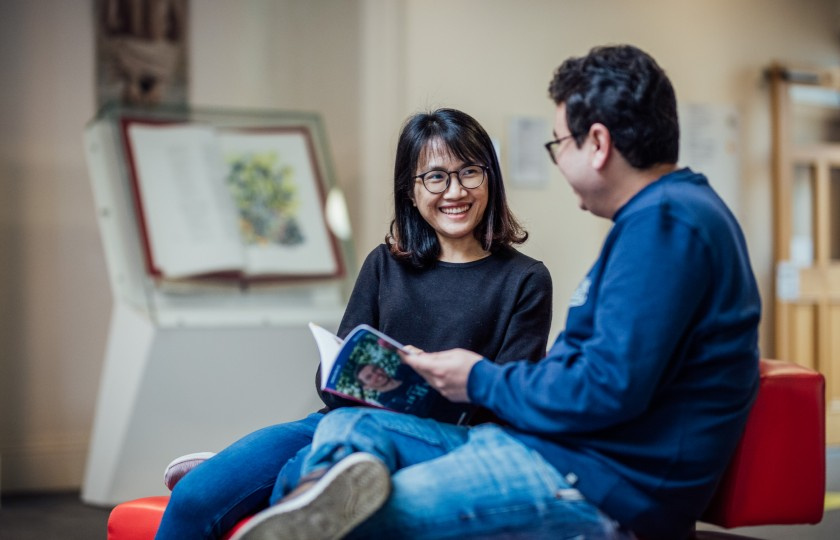 Two students talk while sitting on a couch