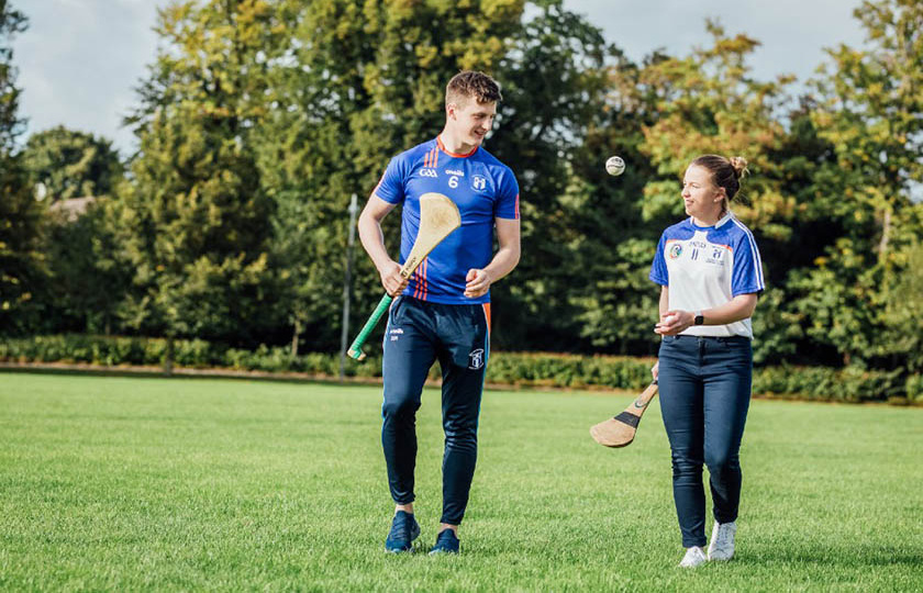 GPA Scholarship recipients holding hurleys and tossing a sliotar between them on the playing pitch at MIC Limerick.