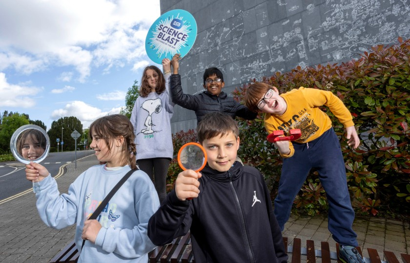 Students holding Science Blast logo in front of MIC building