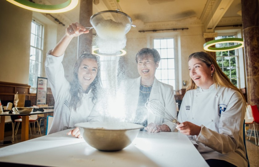 Minister Norma Foley and two students shake flour into a bowl
