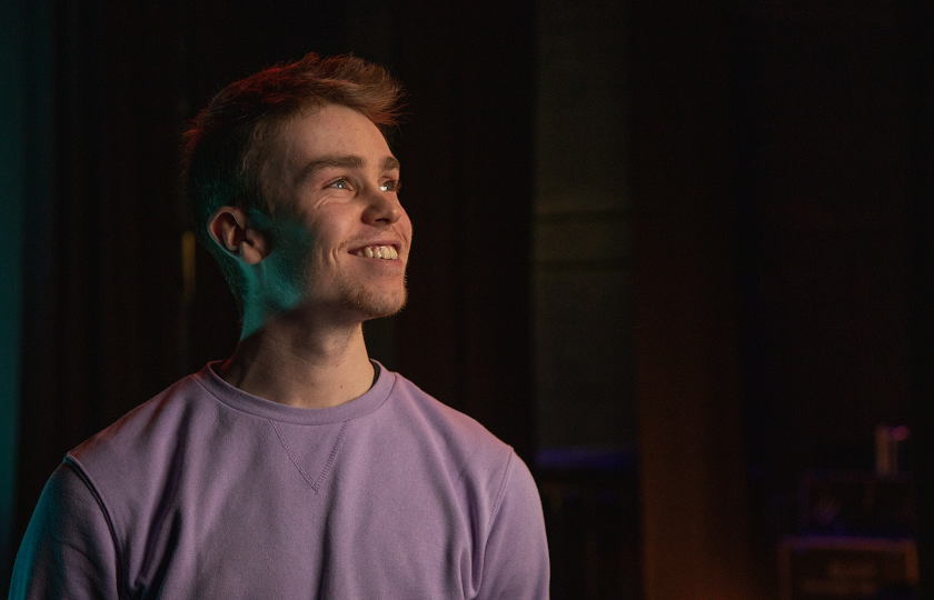  A man wearing a lilac jumper and smiling broadly