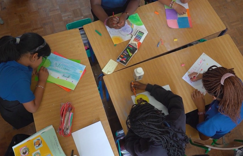 Overhead shot of four female students designing a page saying welcome