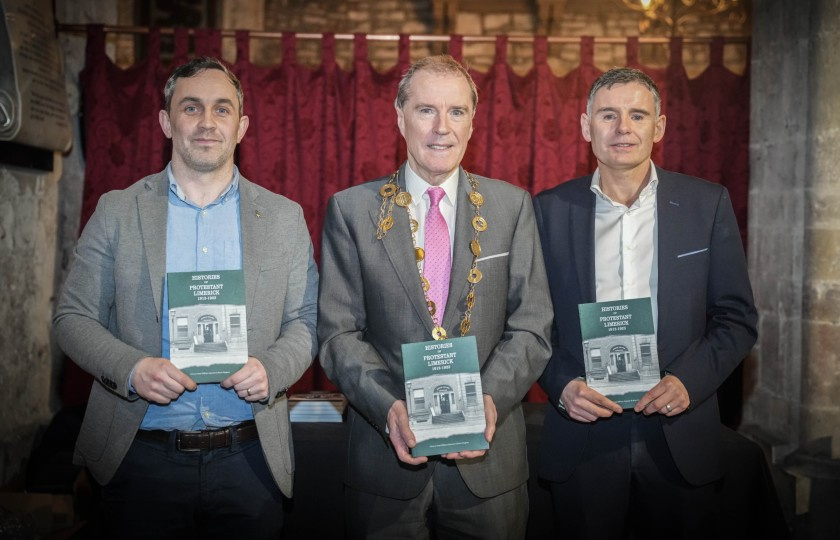 Dr Brian Hughes standing with Mayor of Limerick, Gerald Mitchell and Dr Séan William Gannon at the launch. They are all holding a copy of the book.