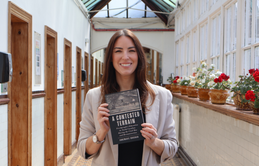 AnneMarie Brosnan holding a copy of her published book, A Contested Terrain