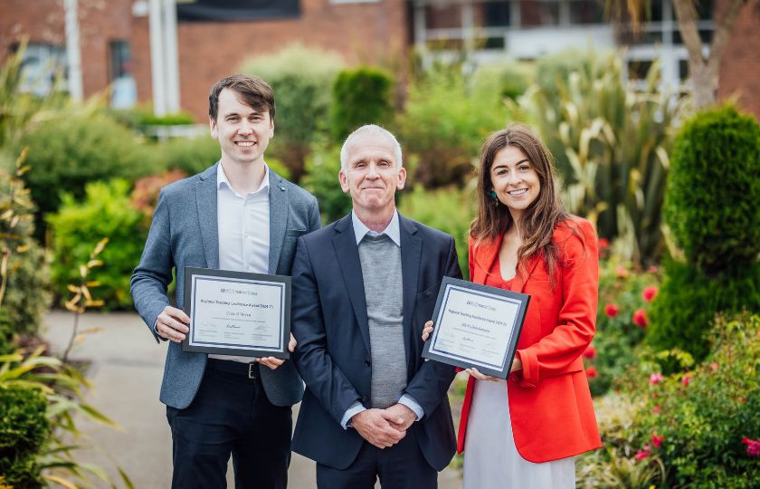 Two teaching fellows with the president of a college posing for a picture with their teaching excellence award