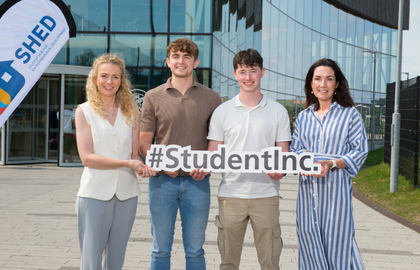Two students entrepreneurs pose for a photo with two female college officials