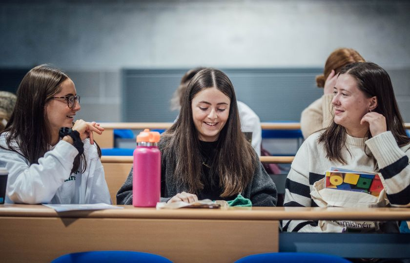 Three newly qualified teachers sitting in a lecture room for a conference