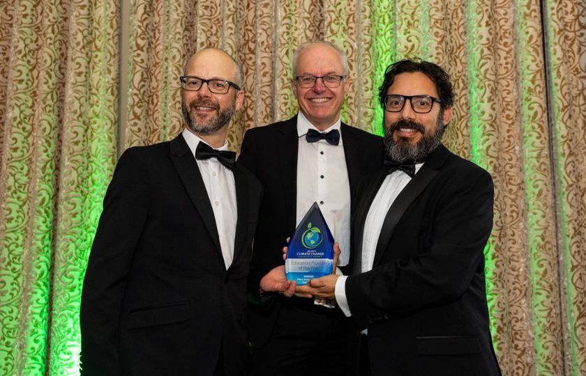 Three men posing for a picture holding an award