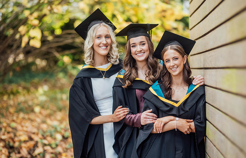 Three students in their graduation robes at MIC graduation ceremonies 2024