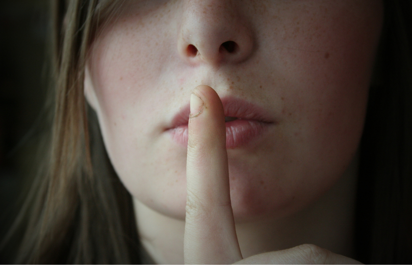 A closeup of a woman ssshing (be quiet)