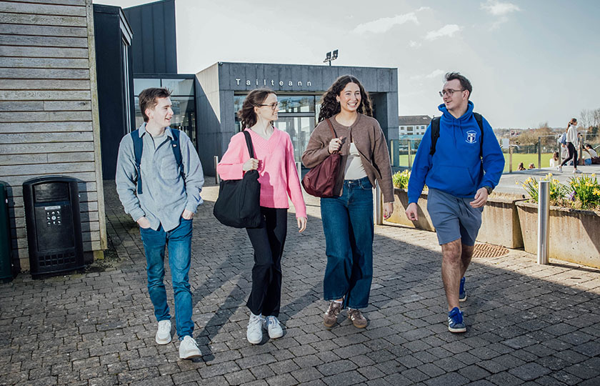 Four undergraduate students walking outside the Tailteann building in MIC