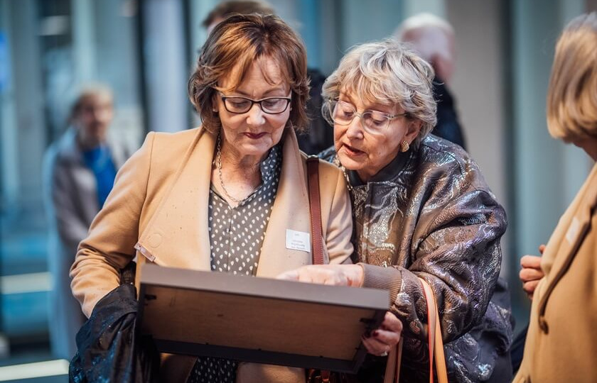 Two attendees of MIC Alumni Reunion 2024 looking at a photo in a frame