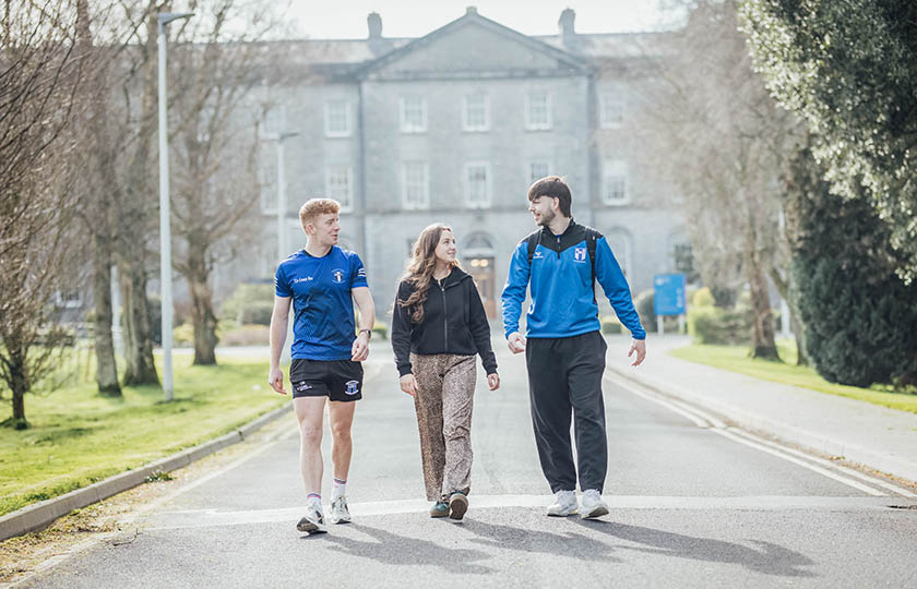 Three students walking down the avenue infront of MIC thurles main building.