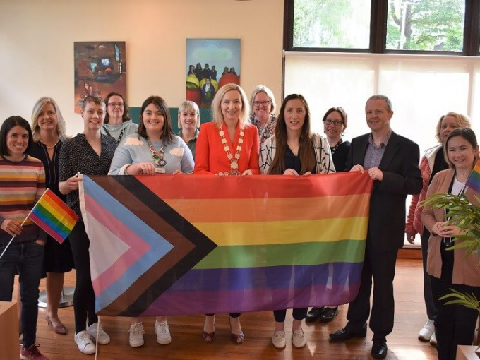 Staff and Cllr. Olivia O'Sullivan with pride flag in staff lounge marking Limerick Pride 2022