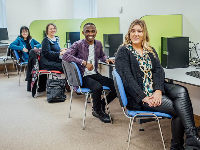 Four students at pcs in MIC college computer room.