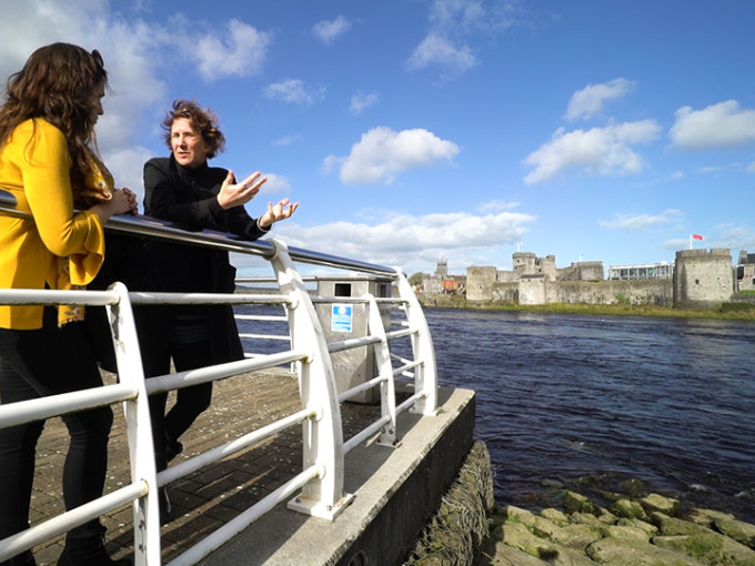 Two women standing at a barrier by the river in Limerick city