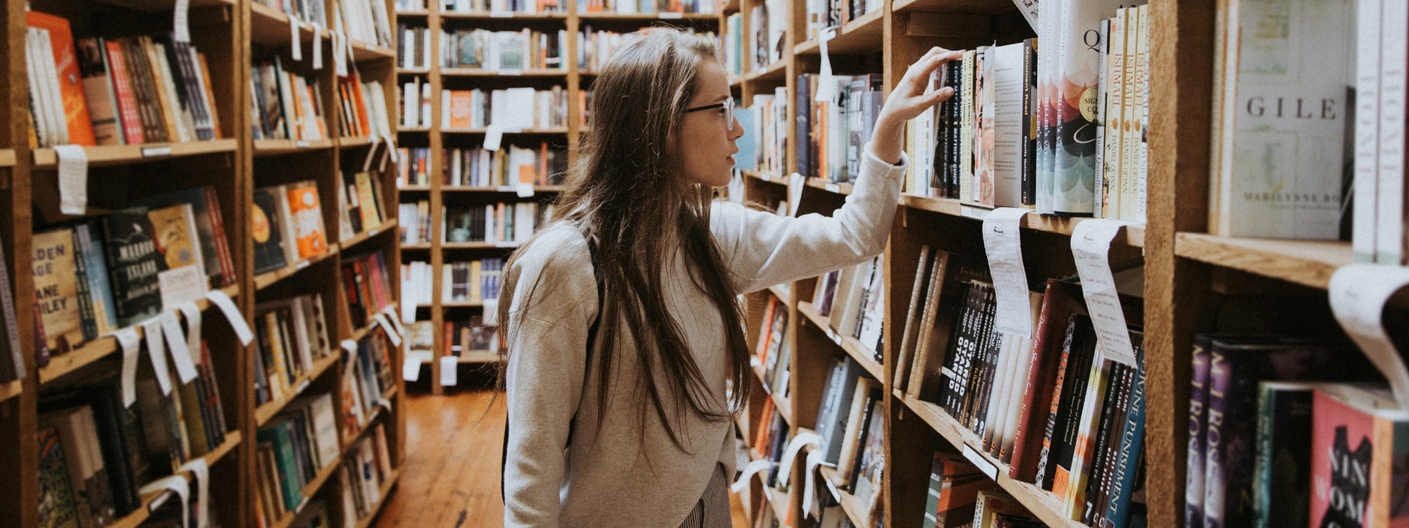 Girl taking a boook from bookshelf